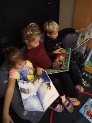 Eine Gruppe von Kindern sitzt auf dem Boden und schaut auf einen Laptop